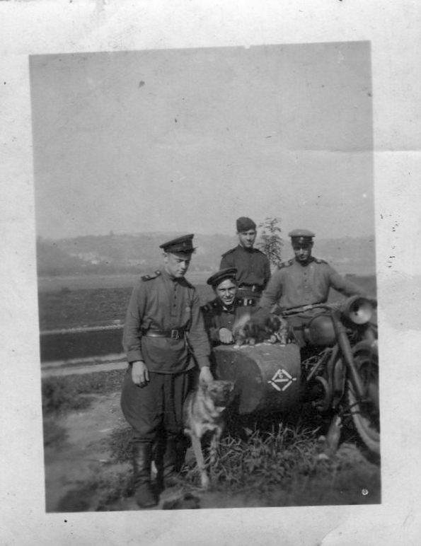 Трое военных в мотоцикле, один стоит рядом с собакой 1950-60